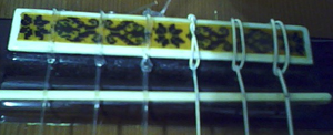 Un puente de una guitarra clásica con su hueso y las cuerdas puestas